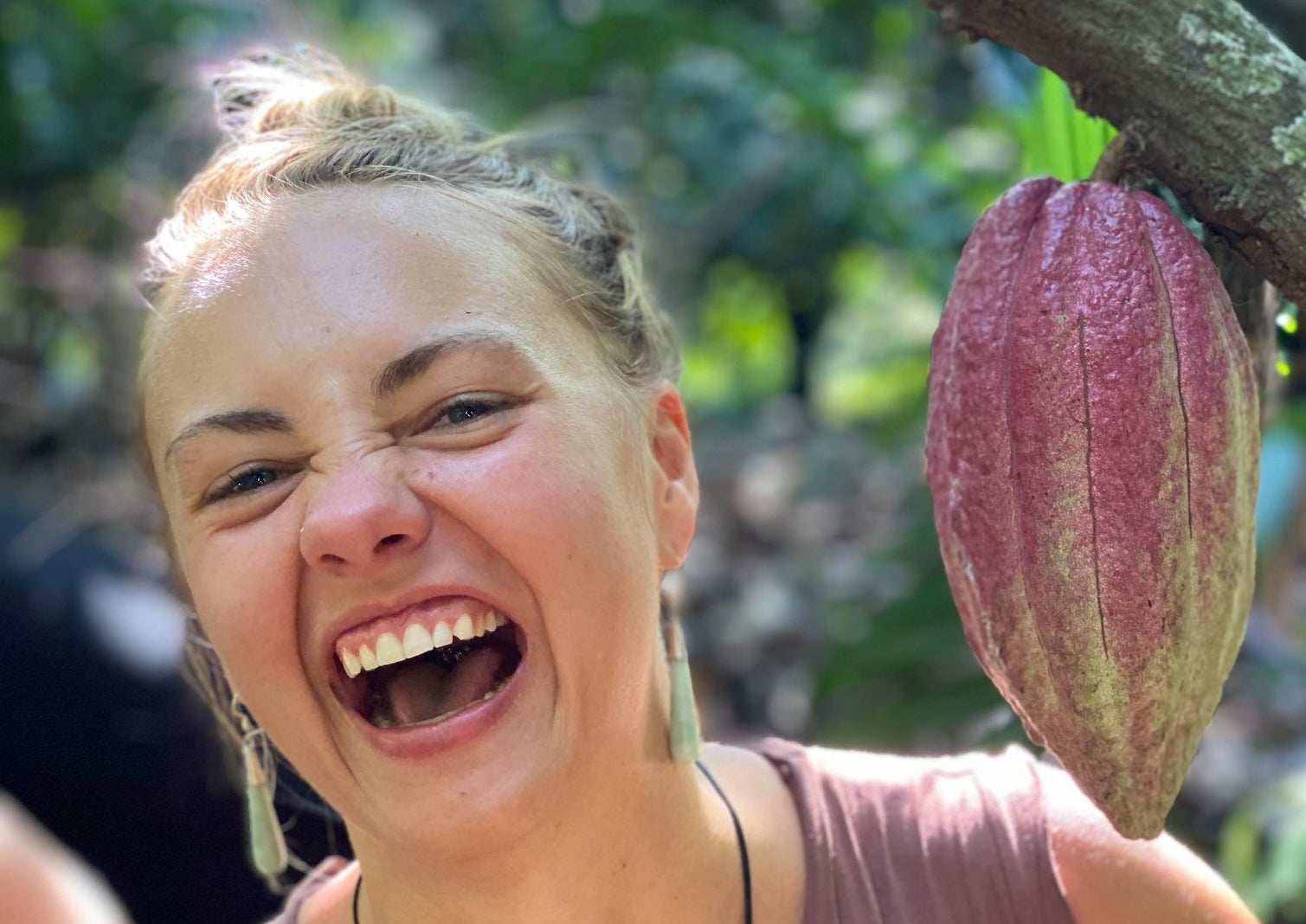 Person with a cacao pod in a natural setting
